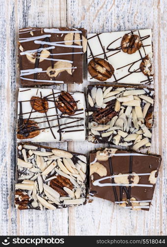 Assorted chocolate caramel bark pieces for sweet dessert arranged on wooden background, top view