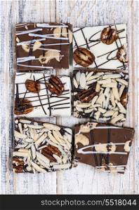 Assorted chocolate caramel bark pieces for sweet dessert arranged on wooden background, top view