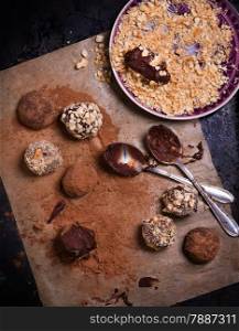 Assorted dark chocolate truffles with cocoa powder, biscuit and chopped hazelnuts over baking paper, selective focus, top view
