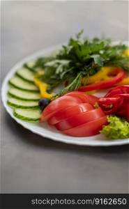 Assorted fresh vegetables on a plate .Dish of cucumbers, paprika, tomato and basil with parsley and cucumber