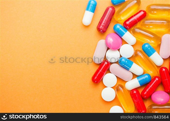 Assorted pharmaceutical medicine pills, tablets and capsules and bottle on orange background. Copy space for text colorful. Assorted pharmaceutical medicine pills, tablets and capsules and bottle on orange background. Copy space for text