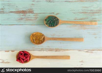 Assorted pharmaceutical medicine pills, tablets and capsules on wooden spoons on vintage wooden table for medicine background