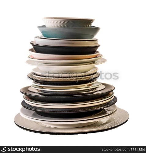 Assorted plates of different shapes, sizes and colours, all stacked one on top of the other, and photographed on a white background.