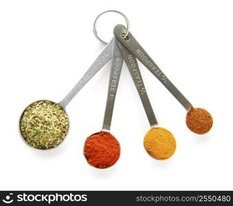 Assorted spices in measuring spoons on white background