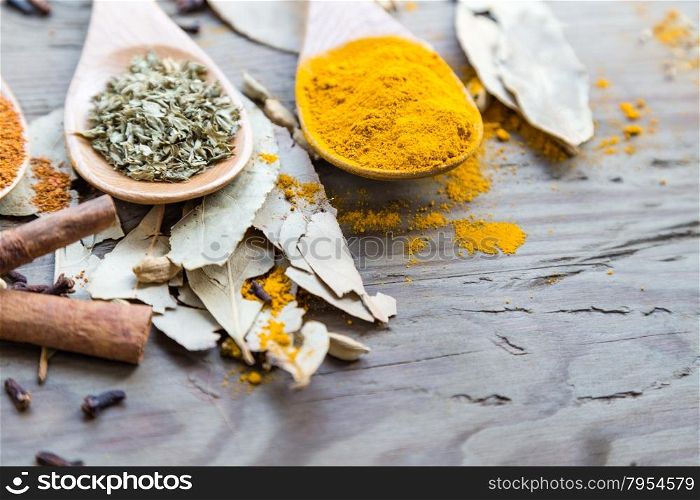 Assorted spices laid out in spoons on a wooden table