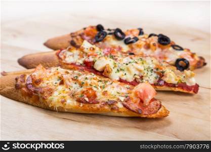 assorti bruscjetta with sausage, cheese, tomato fron big white baguette on wooden background