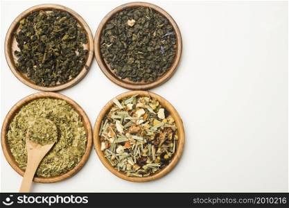 assortment dry medicinal herbs wooden circular plates white backdrop
