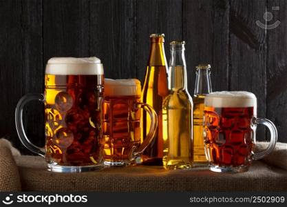 Assortment of beer glasses on table with burlap cloth, dark wooden background