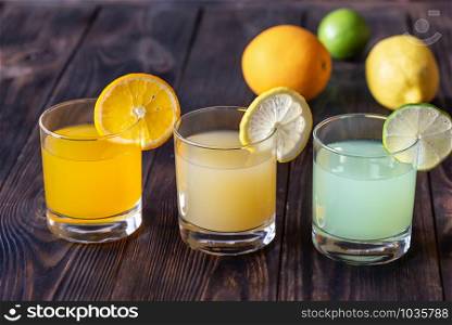 Assortment of citrus juices on the wooden background