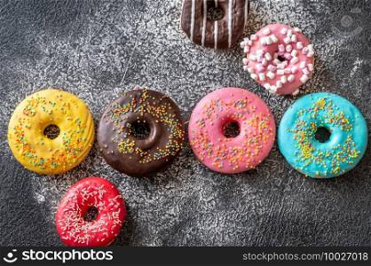 Assortment of colorful donuts on dark background