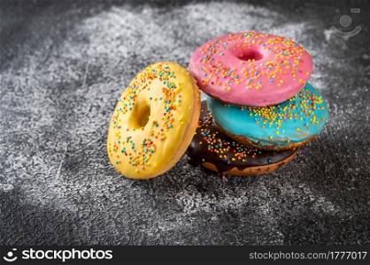 Assortment of colorful donuts on dark background