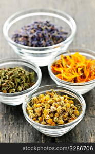 Assortment of dry medicinal herbs in glass bowls