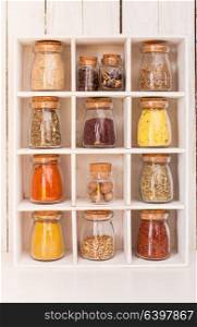 Assortment of dry spices in vintage glass bottles in wooden box. Still life with spices