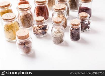 Assortment of dry spices in vintage glass bottles on white background. Still life with spices