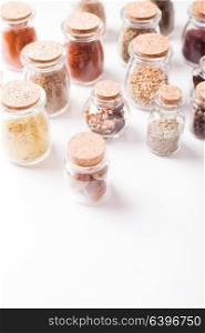 Assortment of dry spices in vintage glass bottles on white background with copy space. Still life with spices