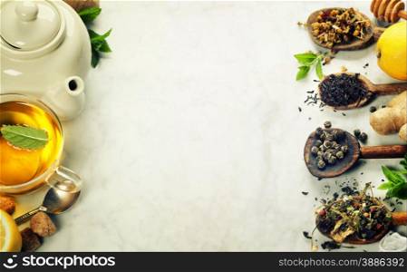 Assortment of dry tea in spoons on marble background