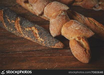Assortment of fresh baguettes close up on a wooden brown background. Baguette on a wooden table