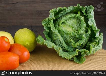 Assortment of fresh cabbages, tomatoes and lemons on brown background