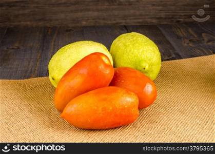 Assortment of fresh tomatoes and lemons on brown background