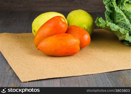 Assortment of fresh tomatoes, lemons and cabbages on brown background