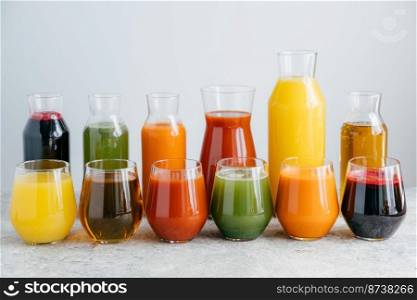 Assortment of jars with tasty multicolored juice, stand on table against white background. Non alcoholic drink. Summer beverage