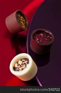 Assortment of luxury white and dark chocolate candies variety on purple and red plate