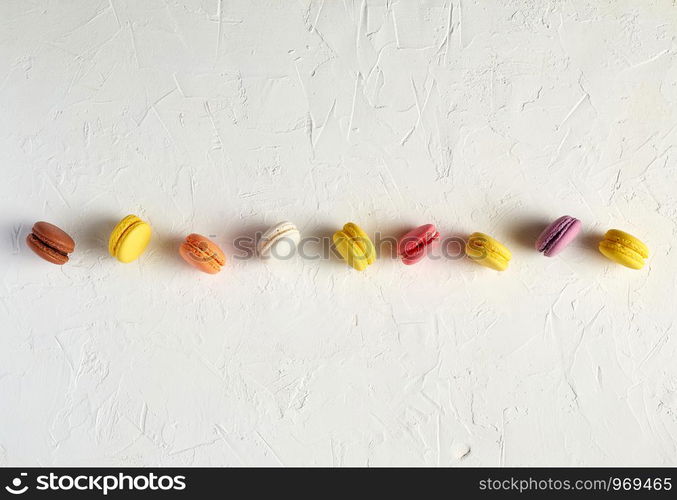 assortment of multi-colored baked round macarons on a white background, flat lay, copy space