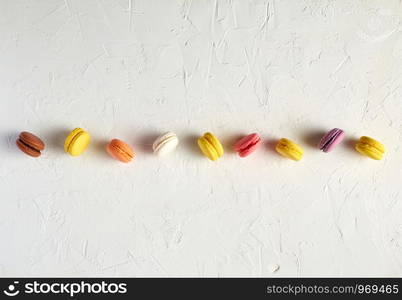 assortment of multi-colored baked round macarons on a white background, flat lay, copy space