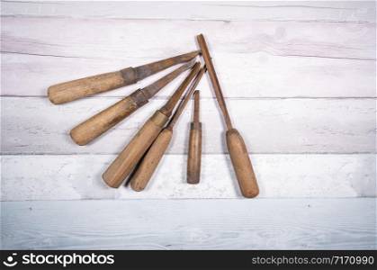Assortment of old wood chisels on a background of old boards. Top view