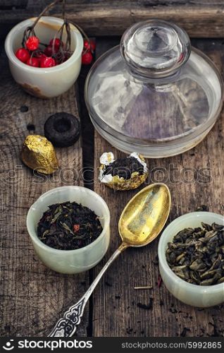 Assortment of tea. cup with tea brewing in the background spoons and viburnum