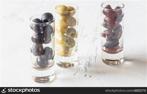 Assortment of three species of olives in glasses on the white background