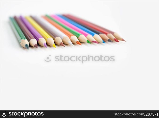 Assorts colorful crayon pencils in row on white background with selective focus on the tip of pencils in the middle on white background. Closeup.