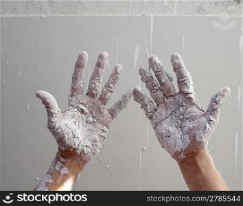 Astist plastering man hands with white dried cracked plaster texture in fingers