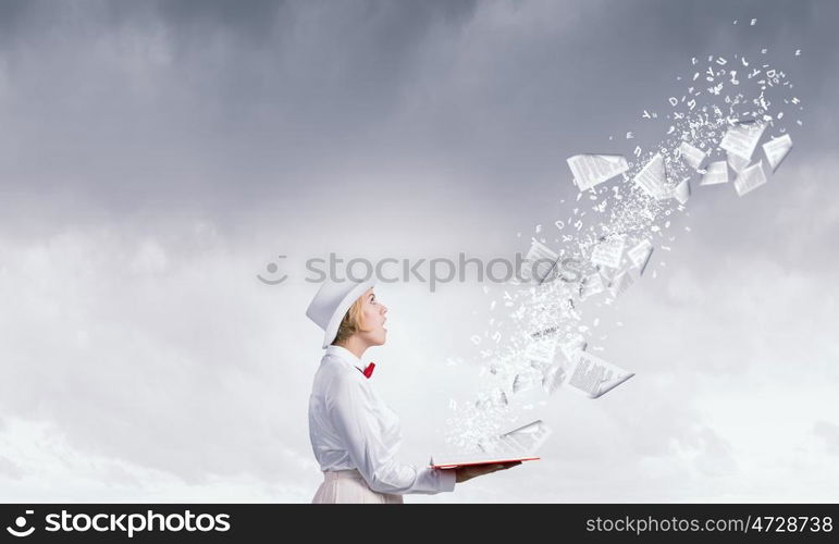 Astonished woman looking in book. Young woman in white hat with opened red book in hands