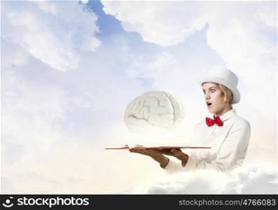 Astonished woman looking in book. Young woman in white hat with opened book in hands and brain on pages