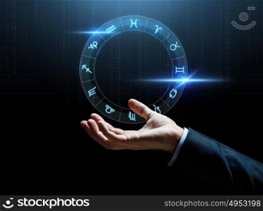 astrology, horoscope, business and people concept - close up of businessman hand with signs of zodiac over dark background. close up of businessman hand with signs of zodiac