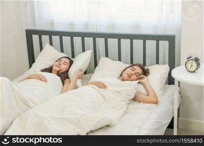 At 7 AM. Two young women roommates sleeping on the bed together in the apartment with morning light. Friend, Friendship, LGBT, lesbian, gay, bisexual.