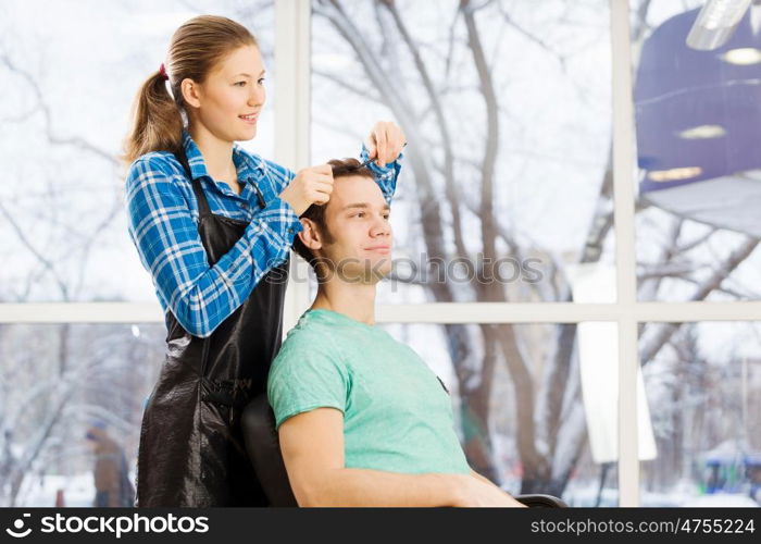 At beauty salon. Young man in chair at barbers and woman hairdresser