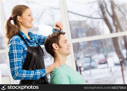 At beauty salon. Young man in chair at barbers and woman hairdresser
