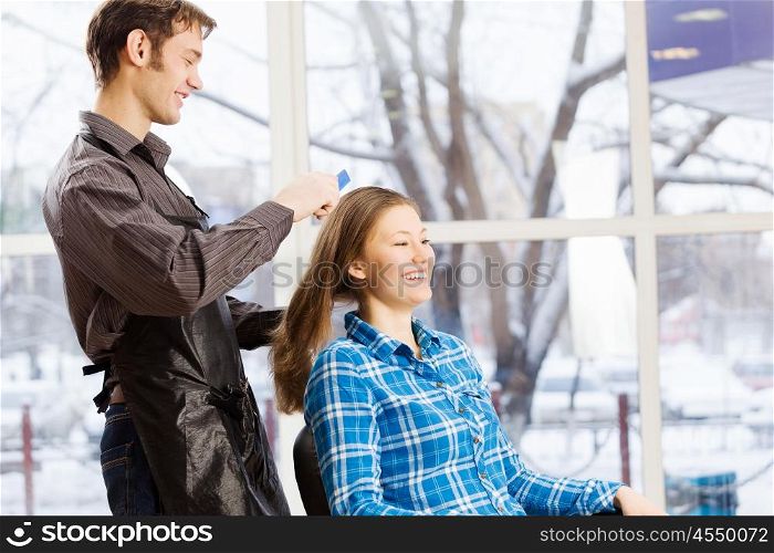 At beauty salon. Young woman in chair at barbers and male hairdresser