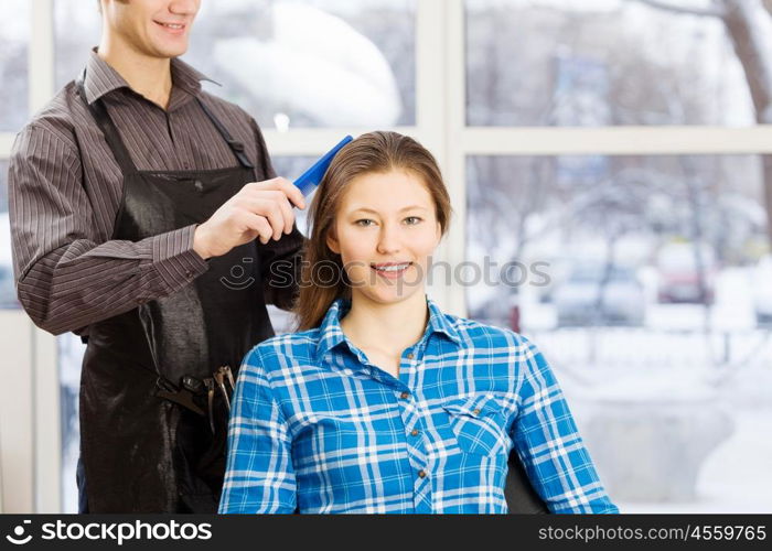 At beauty salon. Young woman in chair at barbers and male hairdresser