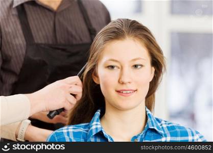 At beauty salon. Young woman in chair at barbers and male hairdresser