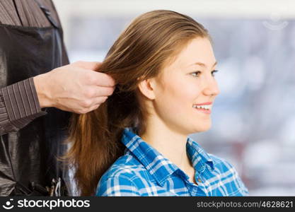 At beauty salon. Young woman in chair at barbers and male hairdresser