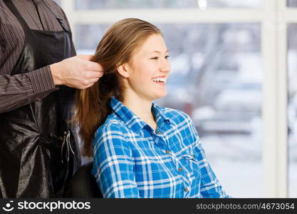 At beauty salon. Young woman in chair at barbers and male hairdresser