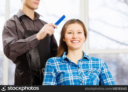 At beauty salon. Young woman in chair at barbers and male hairdresser