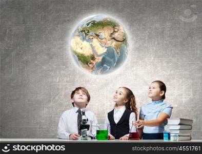 At chemistry lesson. Three cute children at chemistry lesson making experiments. Elements of this image are furnished by NASA