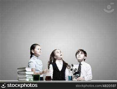 At chemistry lesson. Three cute children at chemistry lesson making experiments