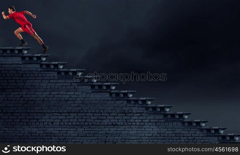 At full speed. Athlete man in red sport wear running up staircase