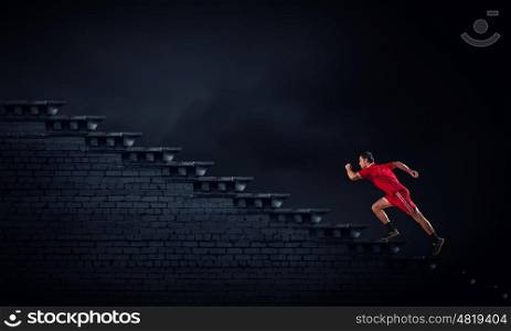 At full speed. Athlete man in red sport wear running up staircase