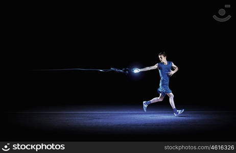 At full speed. Running man in blue sport wear on black background